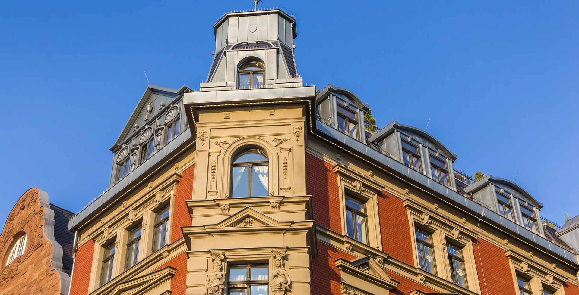 Detailed view of a historic building with decorated windows and a mansard, under a clear blue sky.