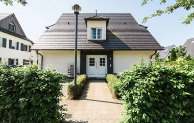 House of the Seezeichen residence in Ahrenshoop with dark roof, hedges and paved path.