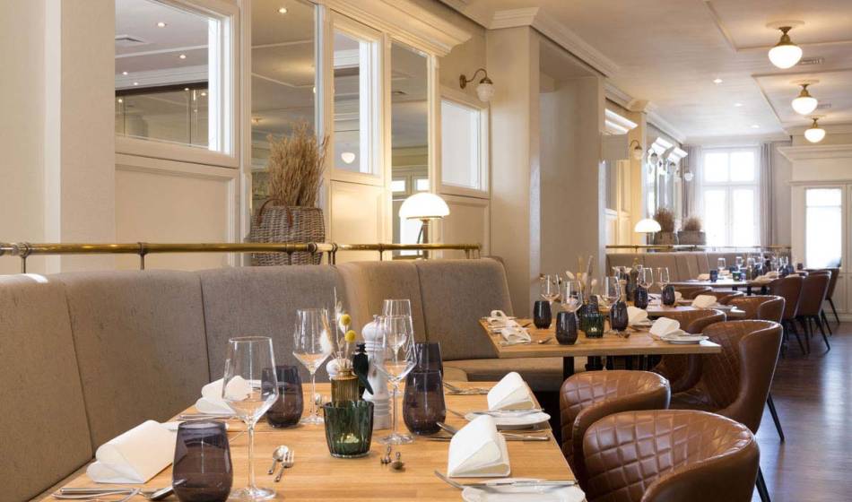 Blick in das Restaurant Strandläufer mit elegant gedeckten Tischen, stilvollen Gläsern und gemütlichen Sitzgelegenheiten.