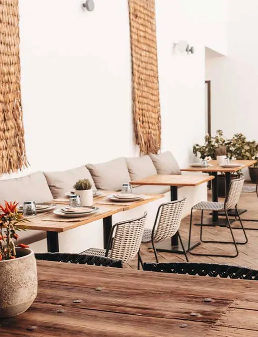 View of the modern Barefoot Restaurant with bright armchairs, wooden décor and laid tables at the Barefoot Hotel on Mallorca.