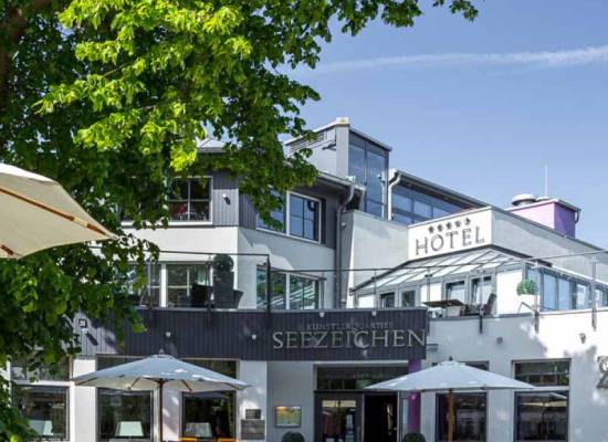 Sunny terrace of the Seezeichen artist quarter in Ahrenshoop with seating and green surroundings.