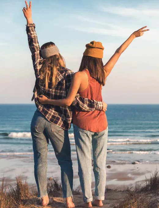 Rear view of two women hugging and enjoying the view of the sea.