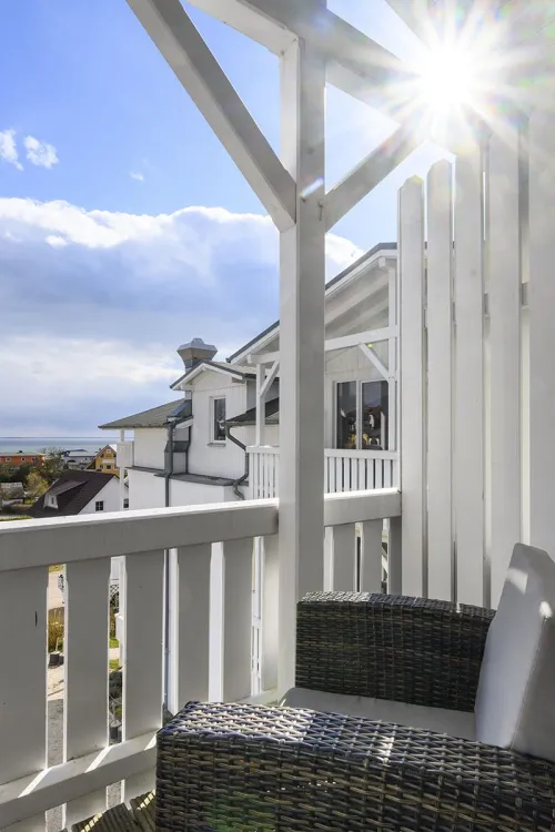 Sunny balcony with rattan furniture in the Koopmanns Hotel and shop on Rügen with a view of the surrounding area.