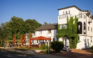 Exterior view of the Elisabeth von Eicken Hotel in Ahrenshoop with parasols and blue sky.