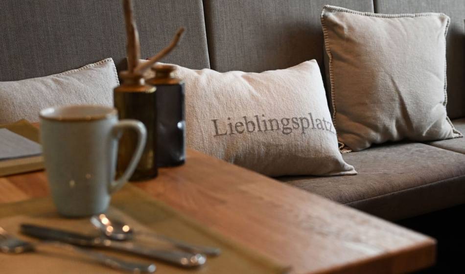 Gemütliche Sitzecke im Strandläufer auf Rügen mit dekorativen Kissen und einladendem Tischgedeck.