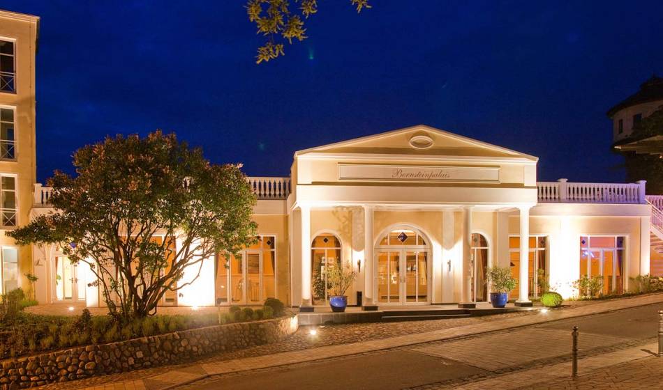 Außenansicht des festlich beleuchteten Veranstaltungsbereichs im Vju Hotel auf Rügen, umgeben von Bäumen bei Nacht.