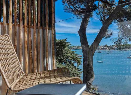 Terrace with views of the sea, wooden furniture and Mediterranean landscape at the Barefoot Hotel Mallorca.