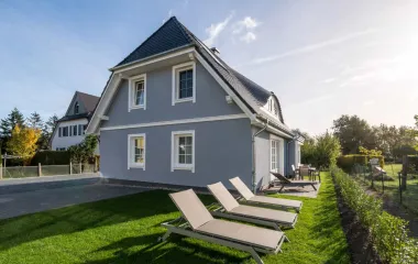 Vacation home Sonneninsel with blue façade, garden, sun loungers and sunny sky in Ahrenshoop.