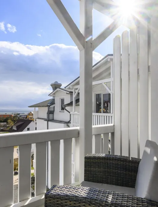 Sunny balcony with rattan furniture in the Koopmanns Hotel and shop on Rügen with a view of the surrounding area.
