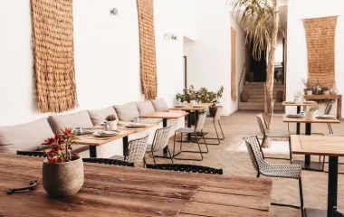 View of the modern Barefoot Restaurant with bright armchairs, wooden décor and laid tables at the Barefoot Hotel on Mallorca.