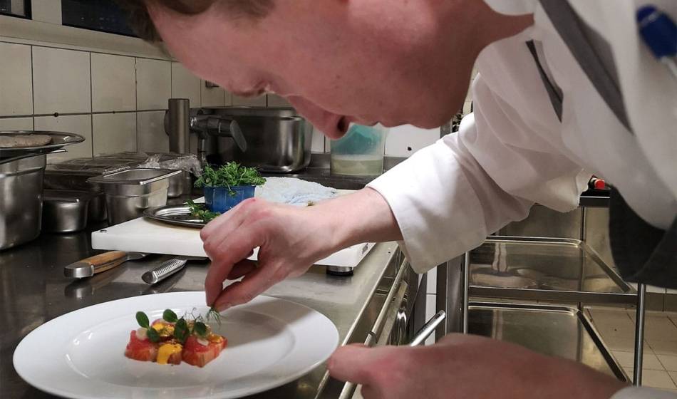 Head chef of the Vju Hotel on Rügen prepares an artistic dish on a white plate with precision.