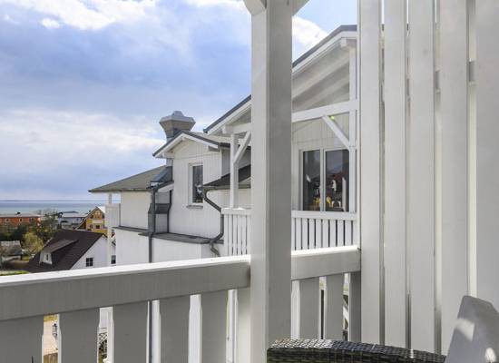 Sunny balcony with rattan furniture in the Koopmanns Hotel and shop on Rügen with a view of the surrounding area.