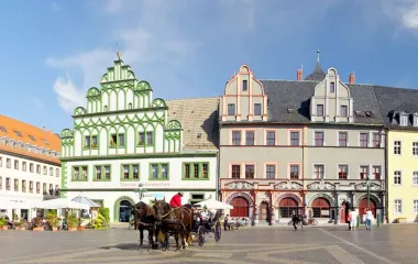 View of the historic city center of Weimar with horse-drawn carriage and people in the background.