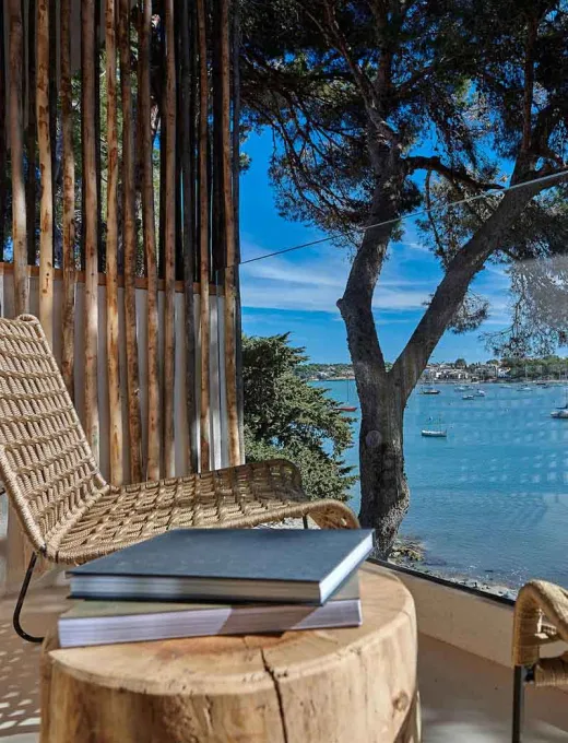 Terrace with views of the sea, wooden furniture and Mediterranean landscape at the Barefoot Hotel Mallorca.