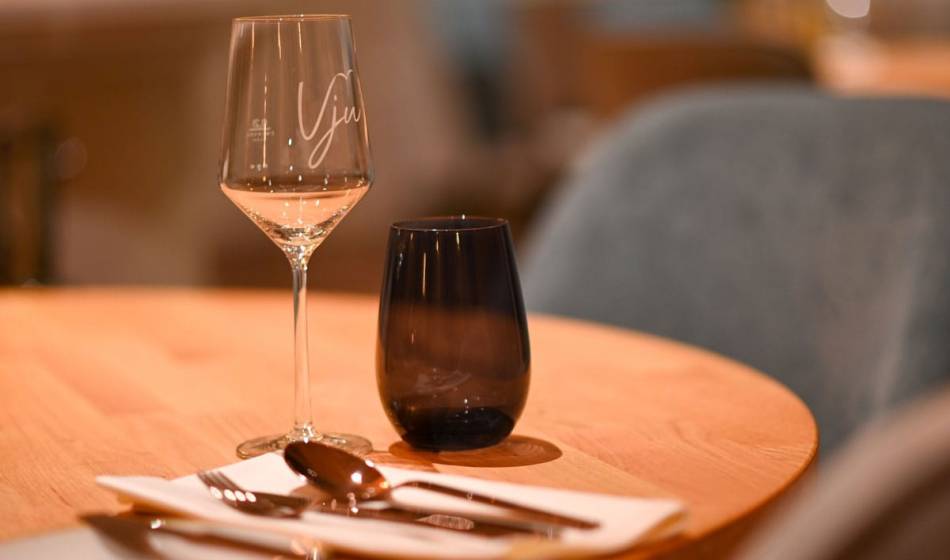 Tischgedeck im Restaurant Strandläufer auf Rügen mit einem Weinglas, Wasserglas und Besteck bereit für Gäste.