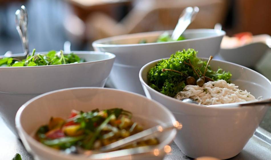Auswahl an Beilagen in Schüsseln, darunter Salat, Kräuter und feine Zutaten, serviert im Restaurant Strandläufer auf Rügen.