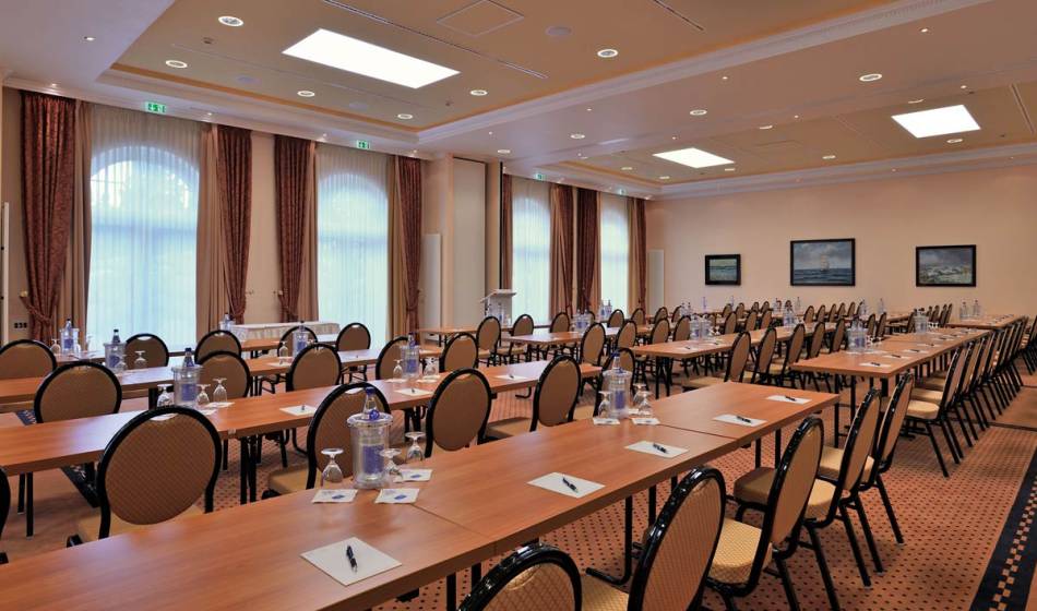 Geräumiger Tagungsraum im Vju Hotel auf Rügen, mit langen Tischen, Stühlen, Wasserflaschen und Schreibmaterial, ideal für Konferenzen.