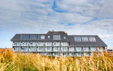Exterior view of the Wyn Strandhotel on Sylt, surrounded by grasses under a slightly overcast sky.