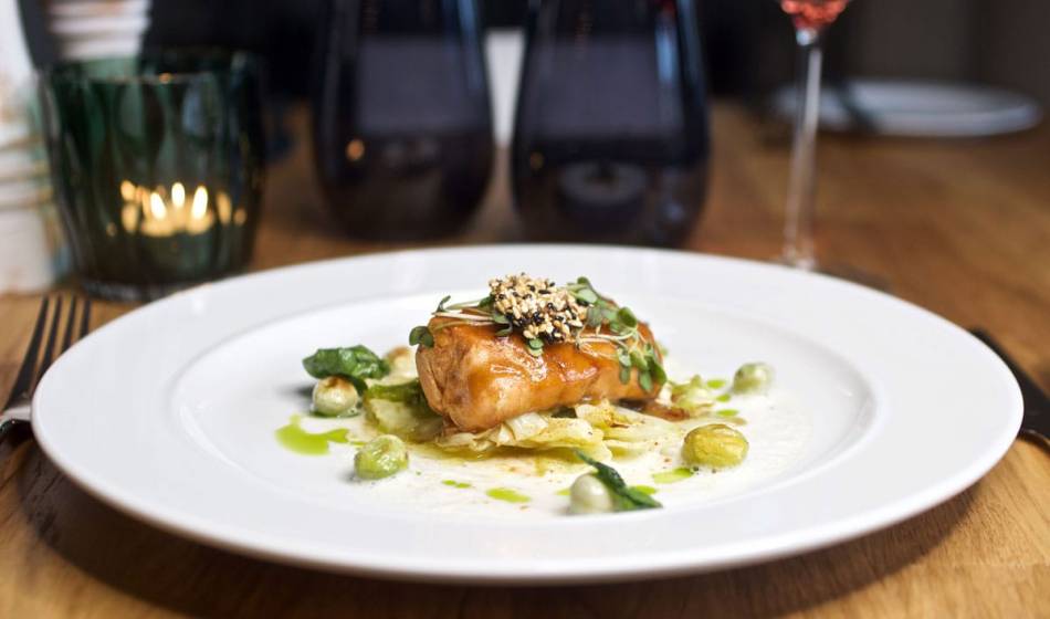 Fein angerichtetes Fischgericht nach Rügener Art, mit Gemüse und Kräutern, stilvoll präsentiert im Restaurant Strandläufer.
