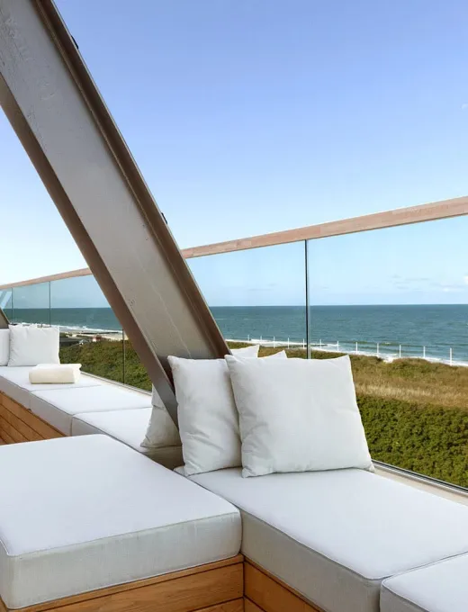 Modern terrace of the Wyn Strandhotel Sylt with white seating and views of the sea and dunes.