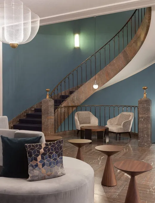 Modern lobby with a curved staircase, stylish armchairs and elegant decor at the Elephant Hotel Weimar.