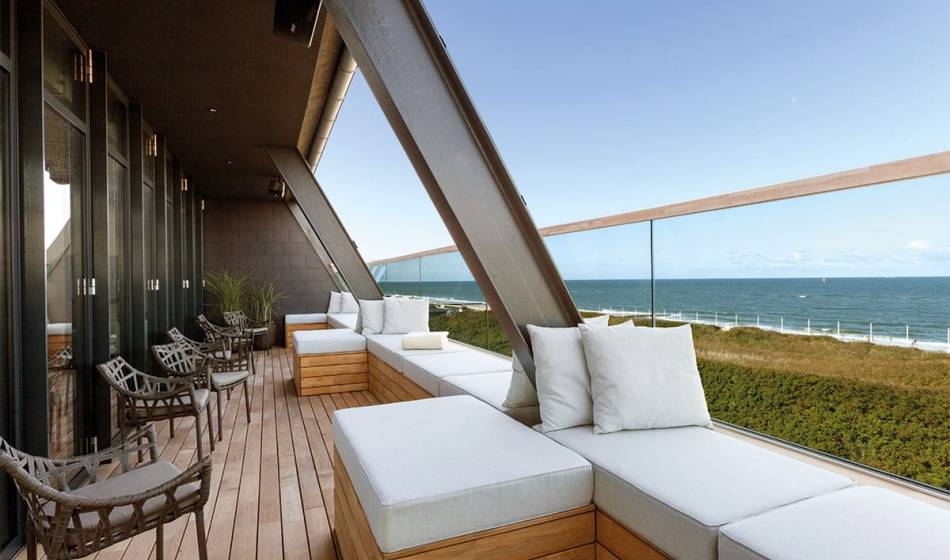 Moderne Terrasse der NIGHT.LOUNGE im Wyn. Strandhotel auf Sylt mit gemütlichen Sitzmöbeln und Meerblick.