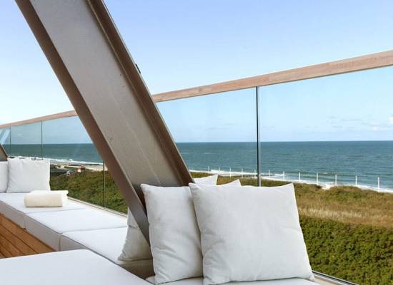Modern terrace of the Wyn Strandhotel Sylt with white seating and views of the sea and dunes.