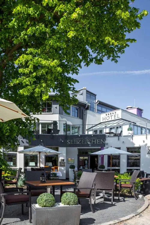 Sunny terrace of the Seezeichen artist quarter in Ahrenshoop with seating and green surroundings.