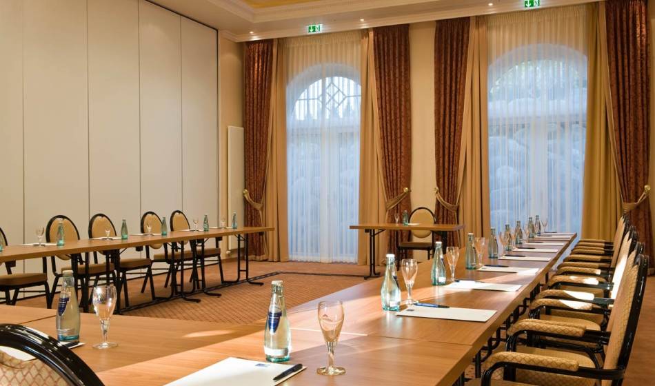 Geräumiger Tagungsraum im Vju Hotel auf Rügen, mit langen Tischen, gemütlichen Stühlen und Ausstattung für Konferenzen.