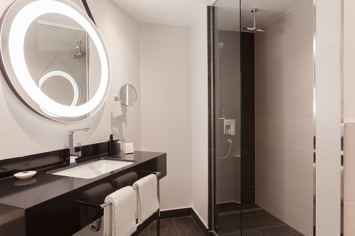 Modern bathroom in the deluxe room at the Hotel Elephant Weimar with glass shower, stylish washbasin and mirror.