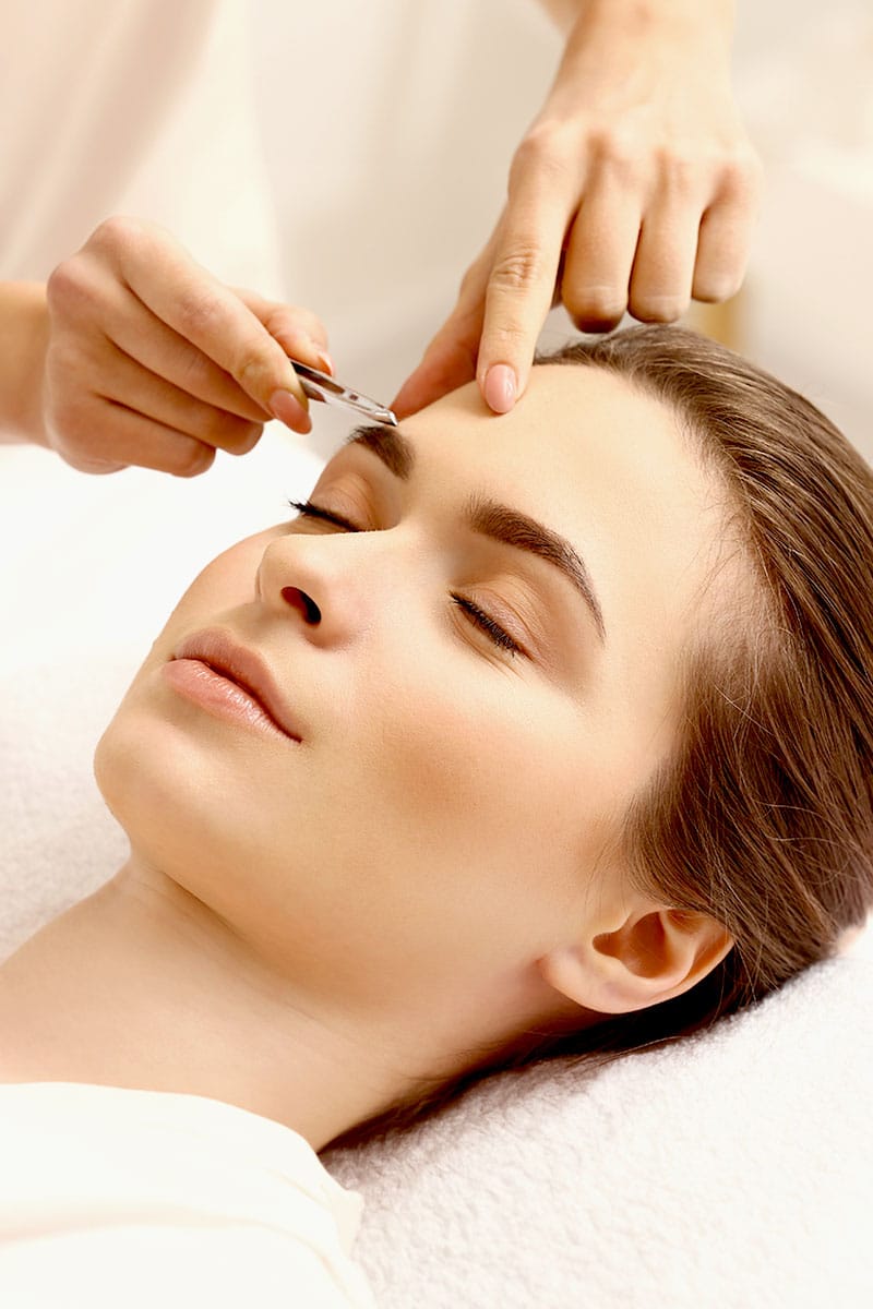Frau bei einer professionellen Augenbrauenkorrektur mit Pinzette im Wellnessbereich des Hotel Kaiserhof Heringsdorf.