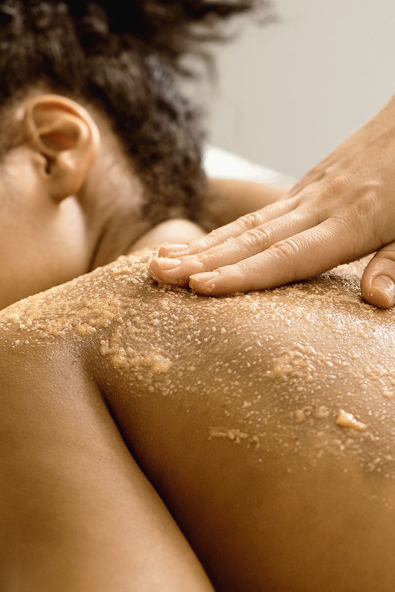 Rücken einer Frau während einer Ganzkörpermassage mit Bernsteinpeeling für gepflegte Haut im Hotel Kaiserhof Heringsdorf.