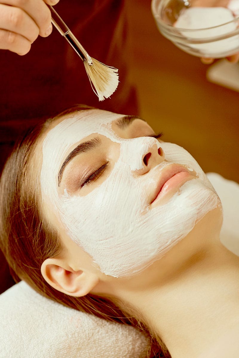 Frau entspannt während einer Gesichtsbehandlung mit aufgetragener weißer Maske im Wellnessurlaub im Hotel Kaiserhof Heringsdorf.