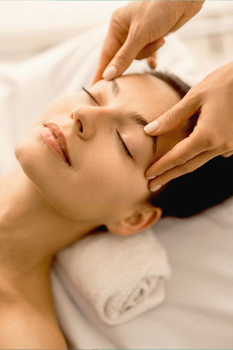 Nahaufnahme einer Frau, die eine beruhigende Gesichtsmassage im Wellnessbereich des Hotel Kaiserhofs in Heringsdorf erhält.