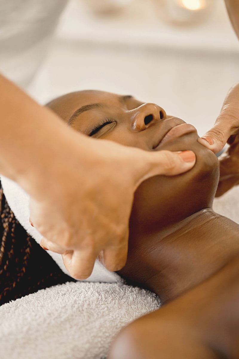 Kosmetikerin massiert sanft die Gesichtskonturen einer entspannten Frau beim Wellness im Hotel Kaiserhof Heringsdorf.