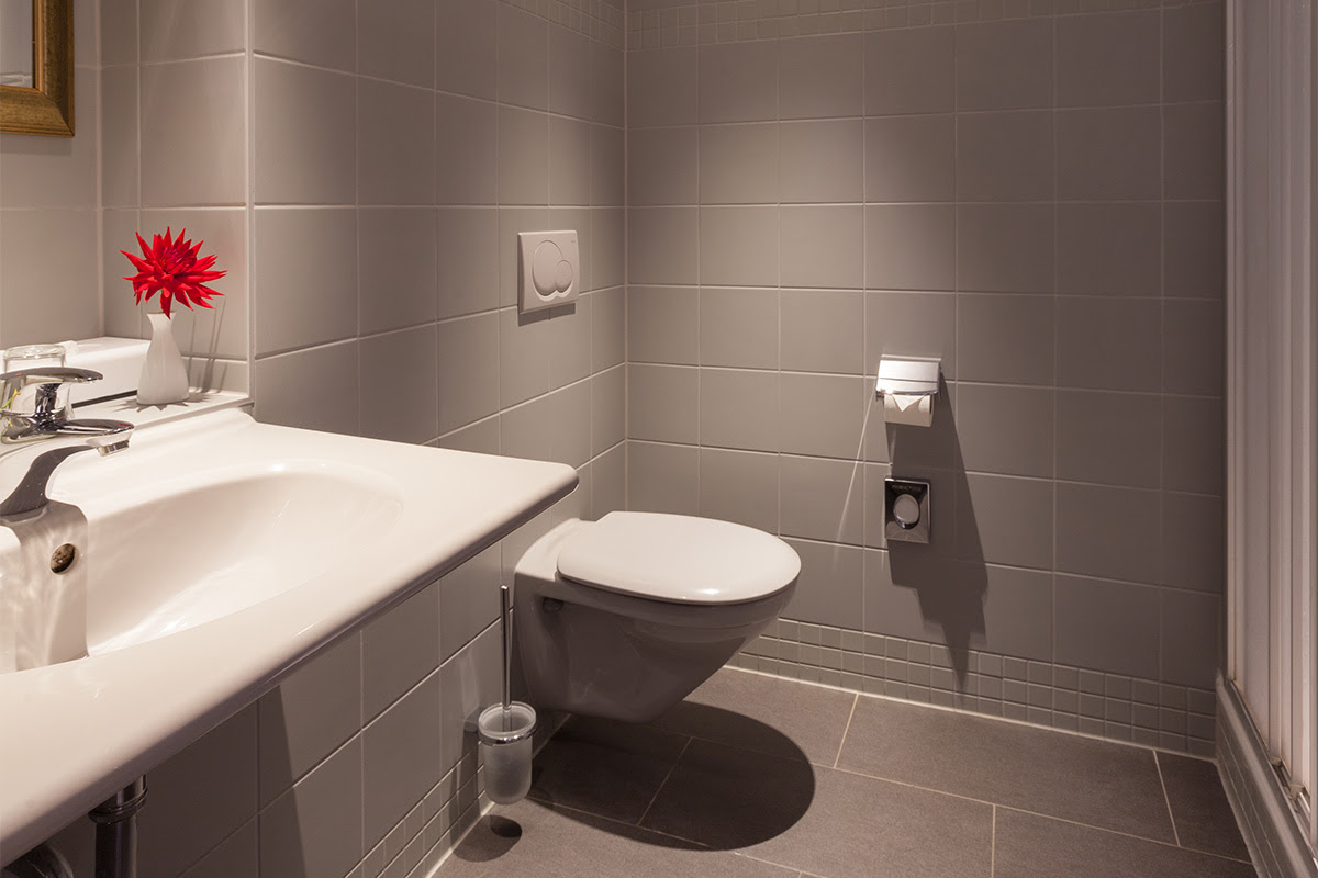 Modern bathroom in the Classic double room with washbasin, WC and gray tiles at the Hotel Kaiserhof Heringsdorf.