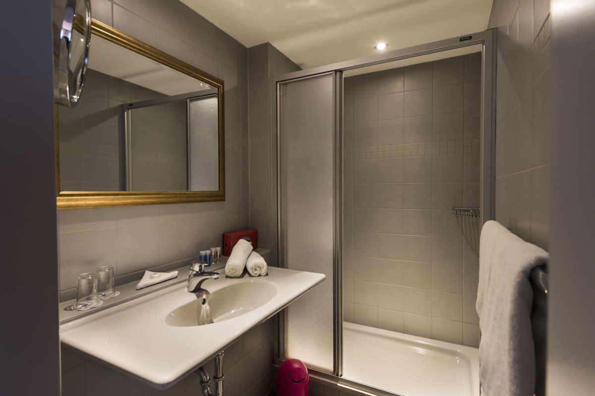 Bathroom in the family room with washbasin, large mirror, shower and towels at the Hotel Kaiserhof Heringsdorf.
