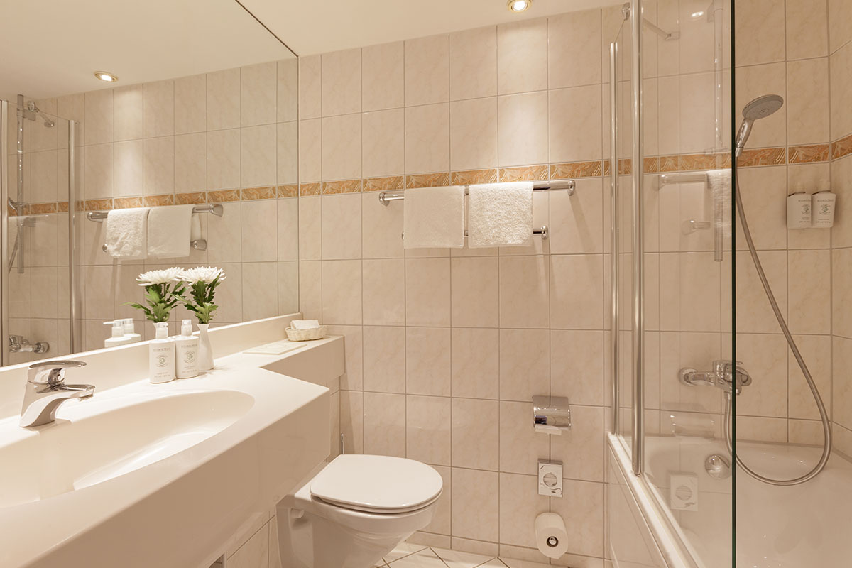 Modern bathroom with glass shower, spacious washbasin and elegant care products at the Hotel Kaiserhof.