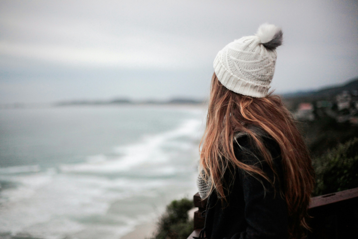 Woman wearing a knit hat looks out over the Baltic Sea and the coastal landscape on Ruegen in an autumn atmosphere