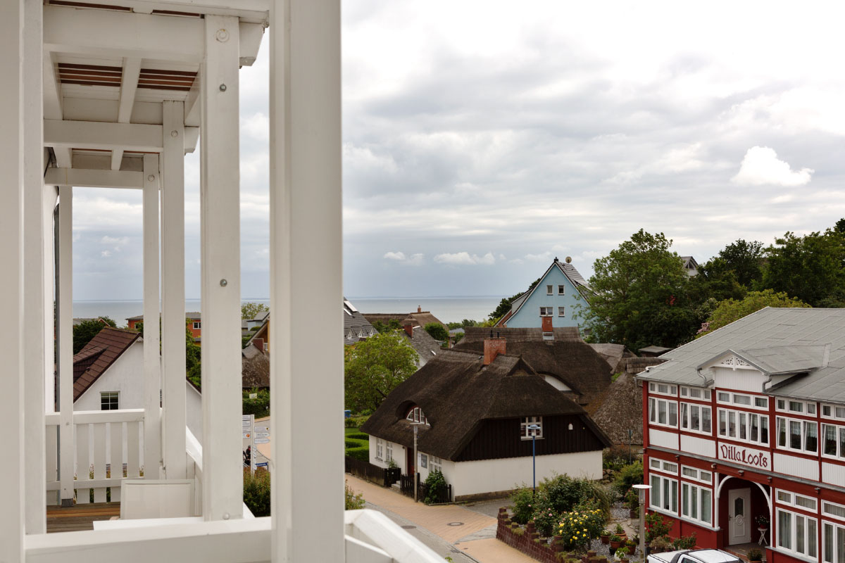 Balcony of a double room at the Koopmanns Hotel with a view of traditional houses and the Baltic Sea in the background.