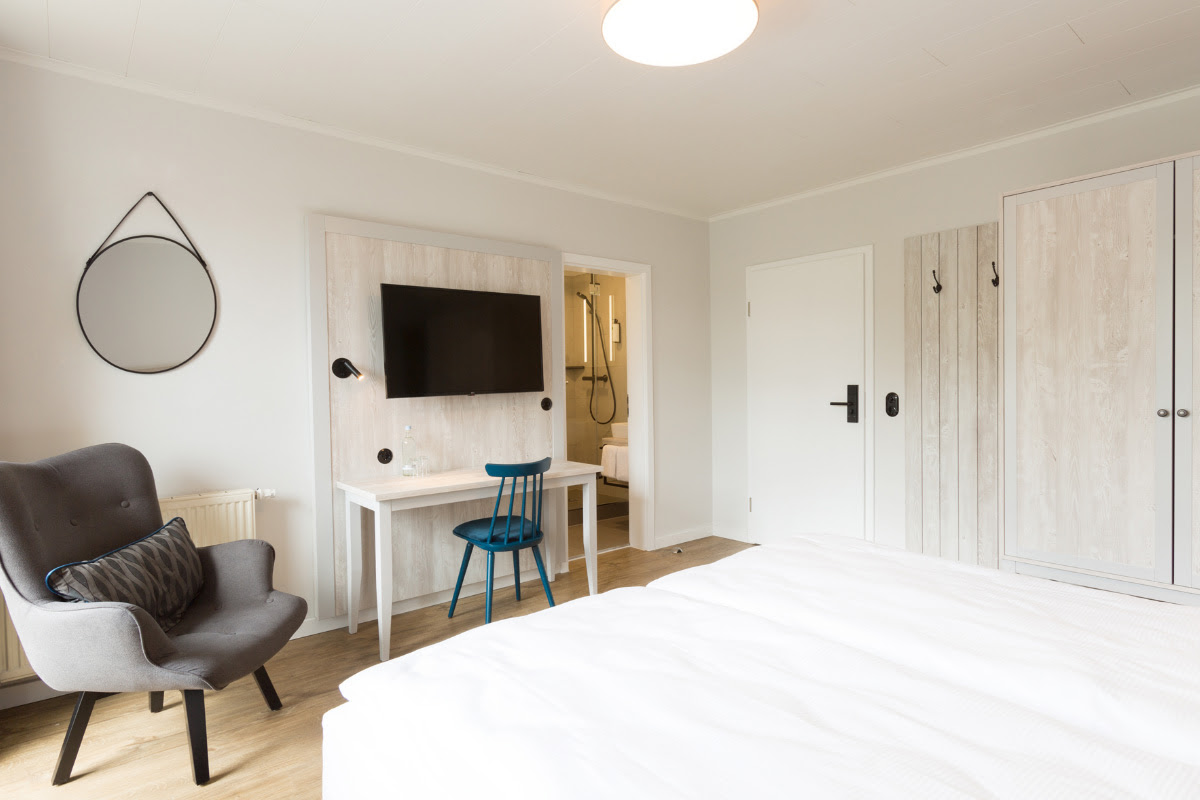 Comfort double room with modern design, equipped with TV, desk and comfortable armchair at the Koopsmanns Hotel.