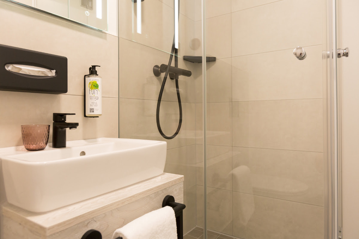 Modern bathroom with walk-in shower, washbasin and mirror at the Koopmanns Hotel &amp; Lädchen.