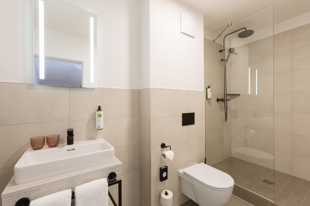 Modern bathroom with clean lines and rain shower in the superior double room at the Koopmanns Hotel &amp; Lädchen in Göhren.