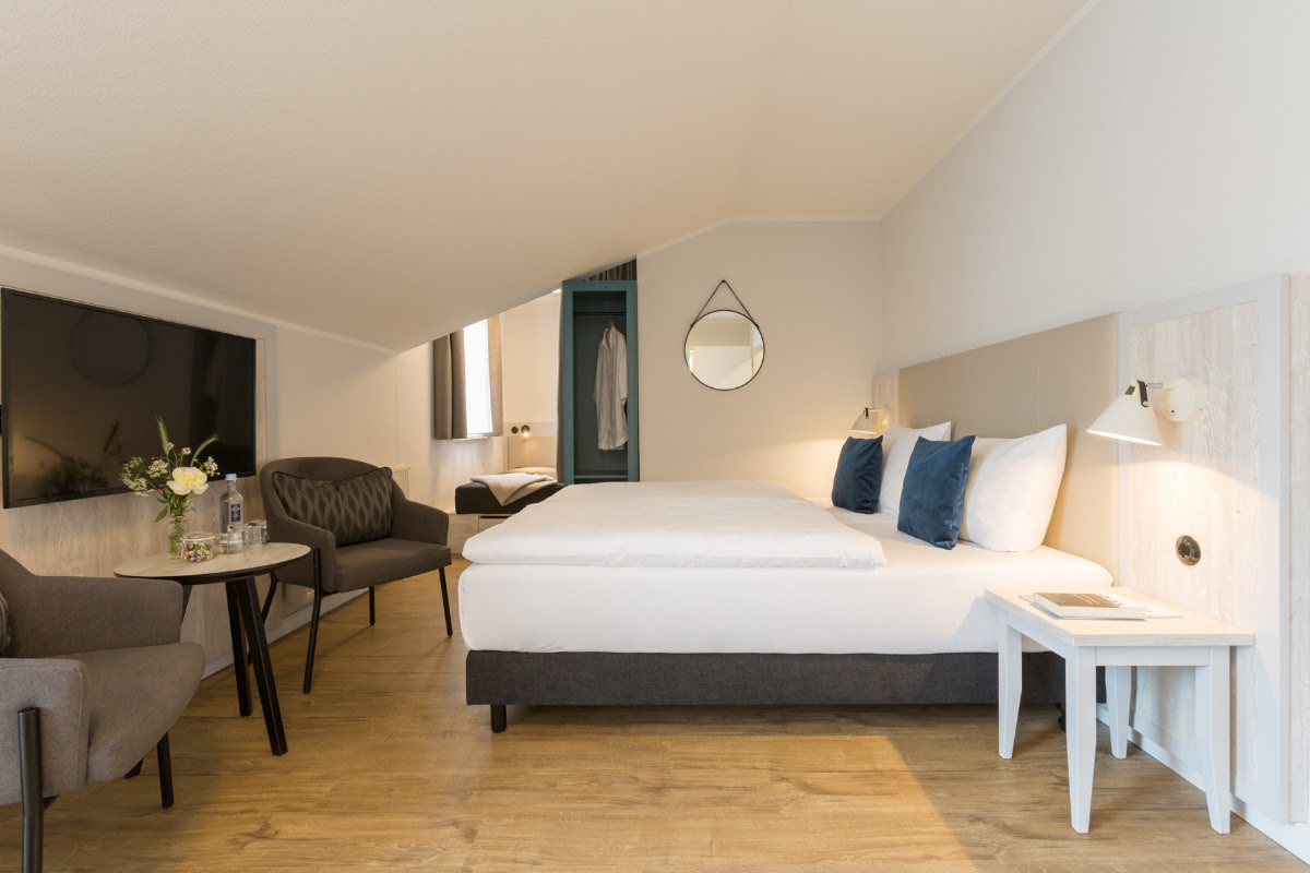 Spacious superior double room with double bed, cozy seating area and modern furnishings at the Koopmanns Hotel.