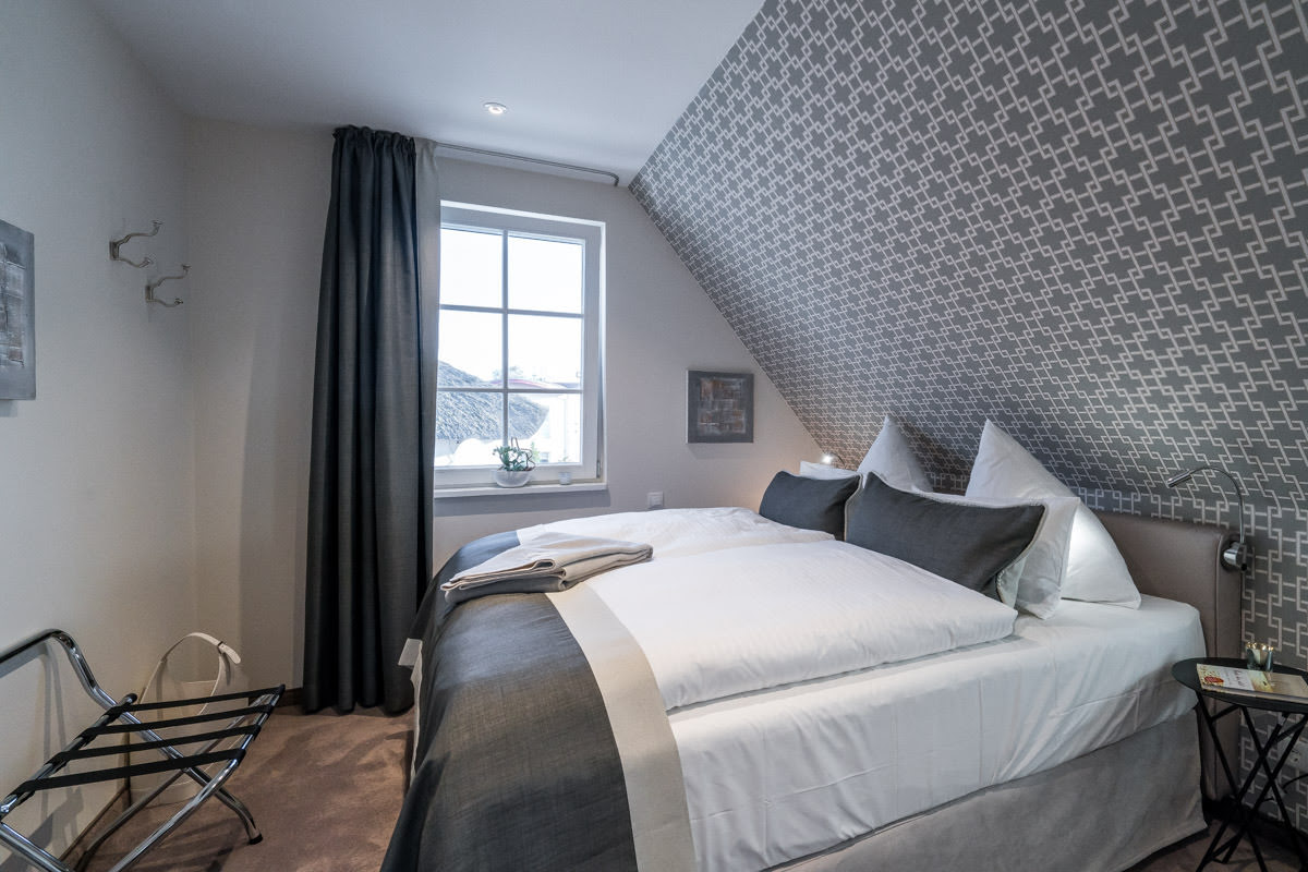 Double bed in the Seewind vacation home at Hotel Künstlerquartier Seezeichen with stylish design and cozy pillows.