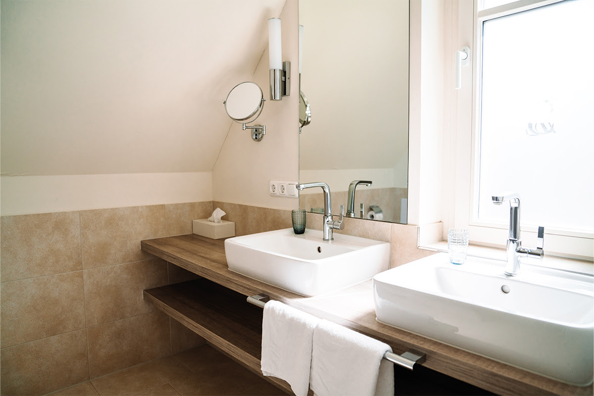 Modern bathroom with two washbasins and daylight in the Dünenpark vacation apartment in the Hotel Künstlerquartier Seezeichen.