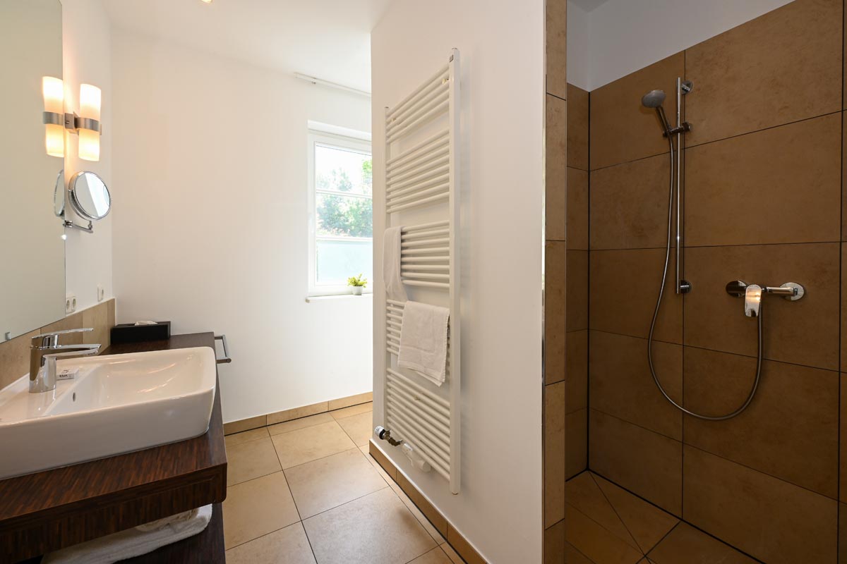 Modern bathroom with walk-in shower, washbasin and heated towel rail in the Seeadler vacation apartment in Ahrenshoop.