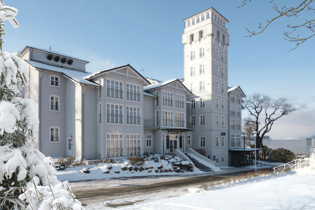 Blick auf das verschneite Vju Hotel Rügen bei blauem Himmel