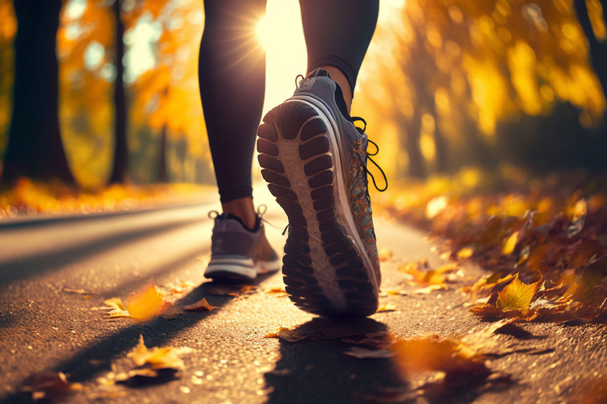 Nahaufnahme von Laufschuhen auf einer herbstlichen Allee mit buntem Laub beim Brennereilauf-Angebot im Vju Hotel.