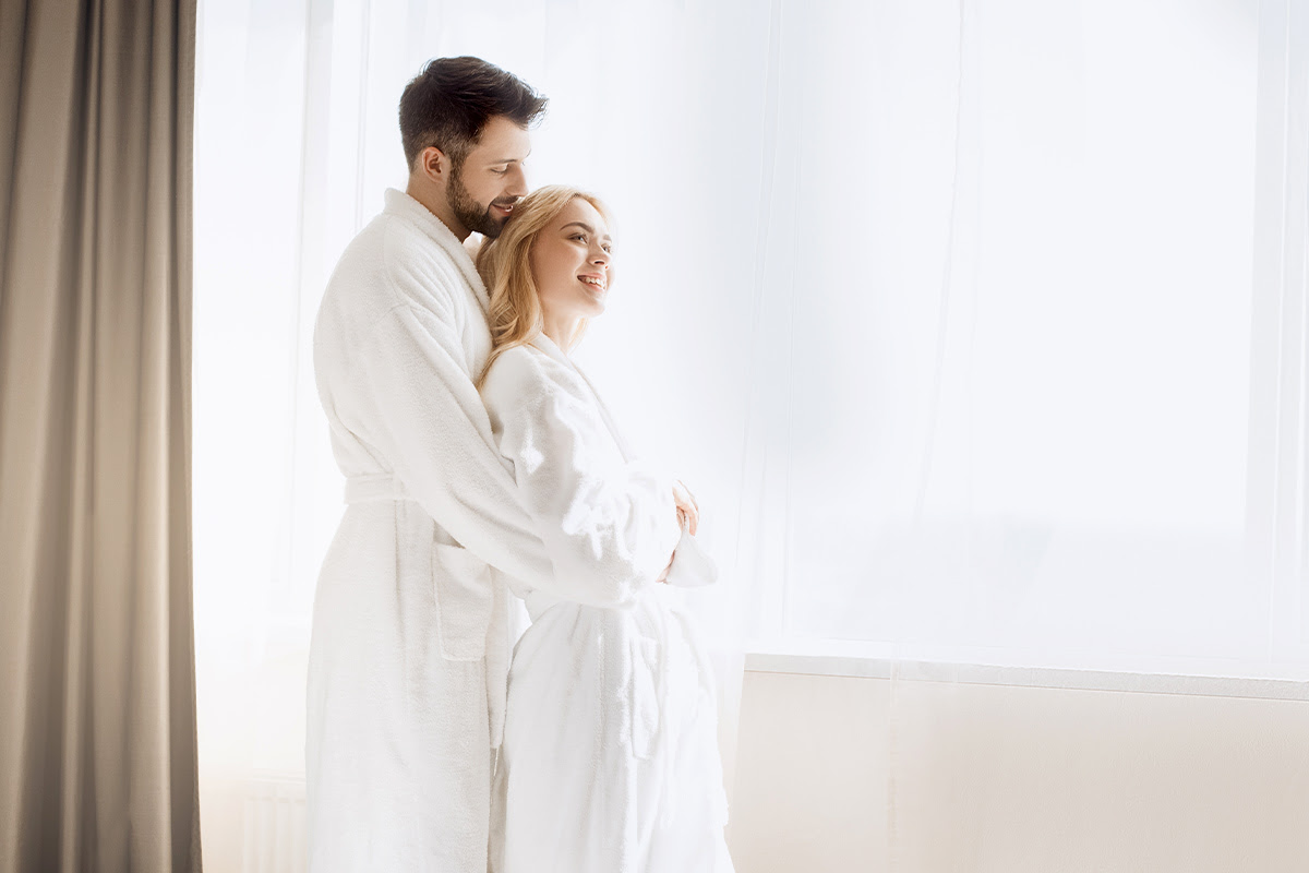 Ein Paar steht in weißen Bademänteln im Wellnessbereich des Vju Hotel Rügen.